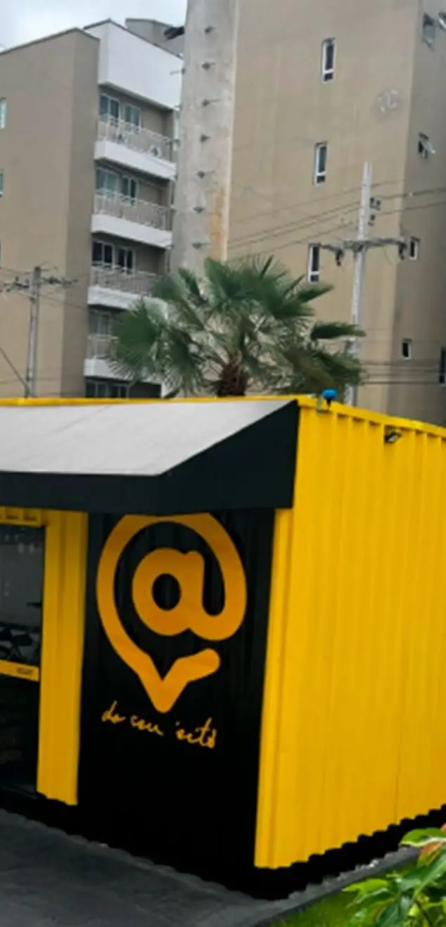 Loja container Armazzem amarela e grafite no térreo de um condomínio, com prédios ao fundo