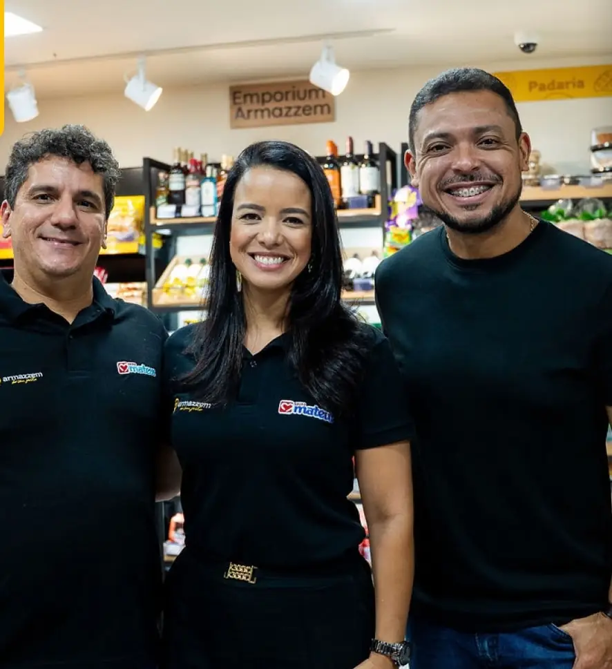 Equipe de três pessoas com uniforme Armazzem sorrindo dentro da loja